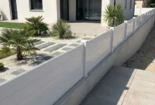 clôture blanche pleine posée sur un petit soubassement autour d'une maison à toit plat