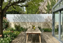 clôture blanche posée sur un muret crépis ton pierre prés d'un terrasse en bois et d'une véranda