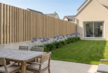 clôture imitation bois à lames verticales ajourées sur un muret dans lotissement de maisons neuves