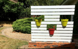 Clôture en pvc blanc brise-vue originale avec l'intégration de pots de fleurs aux différentes couleurs