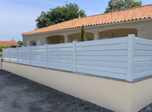 Clôture en pvc blanc brise-vue sur muret installée avec des lames biseautées avec nos chapeaux pvc blanc