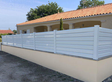 Clôture en pvc blanc brise-vue sur muret installée avec des lames biseautées avec nos chapeaux pvc blanc