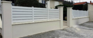Clôture en pvc blanc brise-vue installée sur muret avec boîte aux lettres