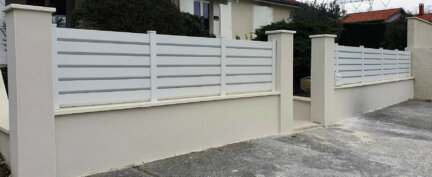 Clôture en pvc blanc brise-vue installée sur muret avec boîte aux lettres