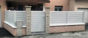Clôture en pvc blanc brise-vue installée sur muret avec portillon