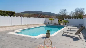 clôture brise vue en pvc blanc coupe irrégulière installée autour d'une piscine