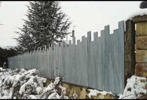 Clôture en pvc gris brise-vue traditionnelle installée sur muret