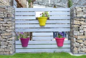 Clôture en pvc gris brise-vue avec l'intégration de pots de fleurs aux différentes couleurs