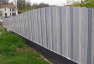 Clôture en pvc gris brise-vue installée avec des lames verticales de 50 mm de large à la coupe irrégulière