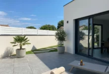 clôture persienne blanche posée sur un muret avec un couvertine en aluminium gris anthracite