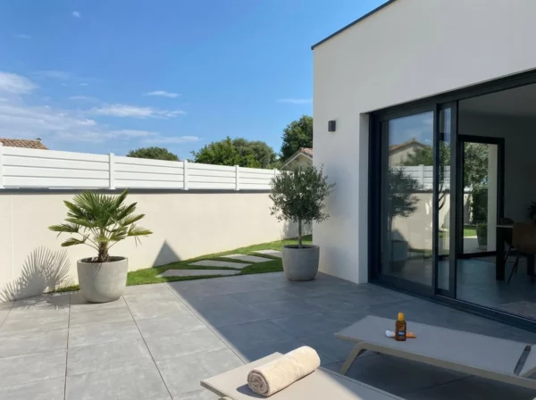 clôture persienne blanche posée sur un muret avec un couvertine en aluminium gris anthracite