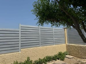 Clôture en persienne PVC Cerbère installée sur muret, occultante, offrant intimité et luminosité dans un jardin moderne.