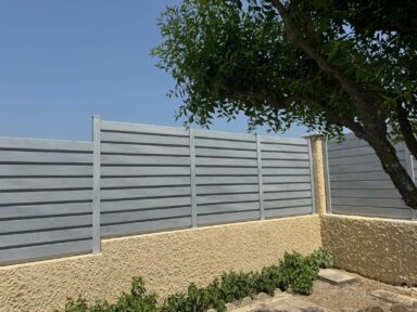 Clôture en persienne PVC Cerbère installée sur muret, occultante, offrant intimité et luminosité dans un jardin moderne.