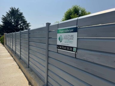 Vue d'une clôture Cerbère en PVC gris, à lames inclinées pour préserver des regards extérieurs tout en laissant passer l'air et la lumière.