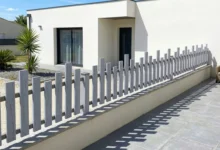 clôture à lames de hauteurs irrégulières ajourée installée autour d'une maison moderne
