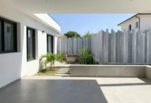 Clôture à lames verticales totalement occultante posée sur une murette prés d'une maison moderne