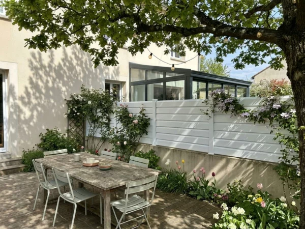 Terrasse ombragée avec clôture PVC persiennée blanche sur muret
