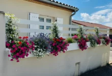 Clôture ajourée blanche installée devant une maison avec des jardinières de fleurs