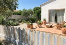 Clôture à lames irrégulières occultantes posée sur un muret dans un jardin esprit botanique