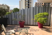 Clôture brise-vue sur terrasse, modèle Sirus gris à lames verticales de hauteurs variées