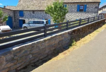 Clôture très ajourée posée sur un muret en pente en pierres naturelles