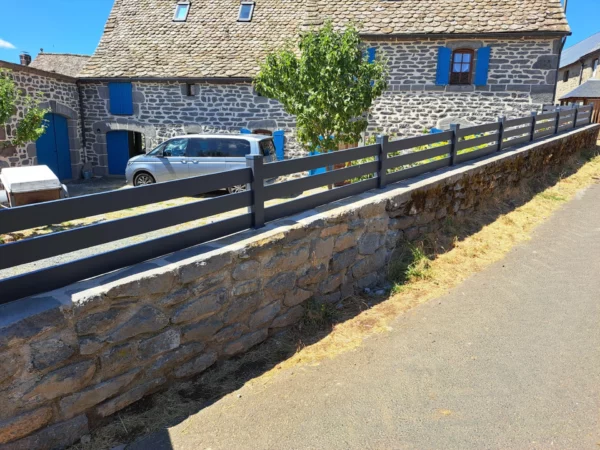 Clôture très ajourée posée sur un muret en pente en pierres naturelles
