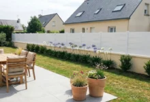 Clôture bise vue installée sur un muret avec des fleurs de type agapanthes