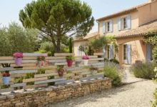 Clôture destructurée installée sur un muret en pierre dans le jardin d'un mas provencal