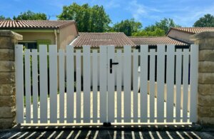Clôture pvc blanc et portail battant en pvc blanc ajouré installées avec différentes largeurs de lames espacées de 30 à 50 mm