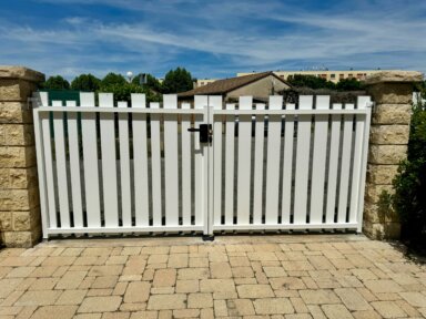Clôture pvc blanc et portail battant en pvc blanc ajouré installées avec différentes largeurs de lames espacées de 30 à 50 mm