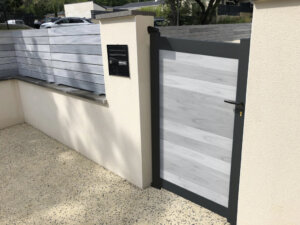 Portillon Negus lames horizontales gris cérusé installée avec une clôture assortie