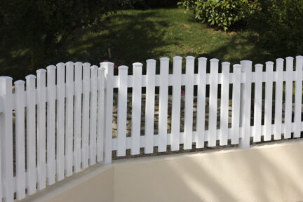 Clôture en pvc blanc ajourée installée avec des lames verticales en coupe bombée pour aménager votre jardin