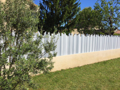 Clôture en pvc gris brise-vue installée sur muret pour apporter une touche d'originalité à votre maison