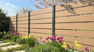 clôture imitation bois moderne avec poteaux anthracite, installée dans un jardin fleuri