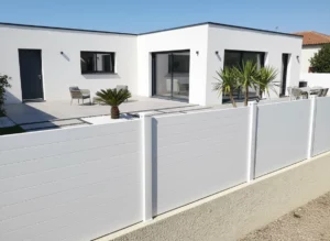 clôture pleine blanche fixée sur un muret en parpaings enduit autour d'une maison neuve