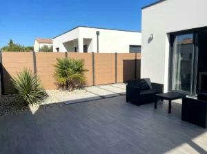 clôture beige en composite posée en pleine terre dans un jardin