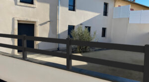 Clôture en pvc plaxé gris anthracite ajouré installée sur muret avec un espacement de 100 mm entre chaque lames horizontales