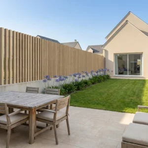 clôture imitation bois à lames verticales ajourées sur un muret dans lotissement de maisons neuves